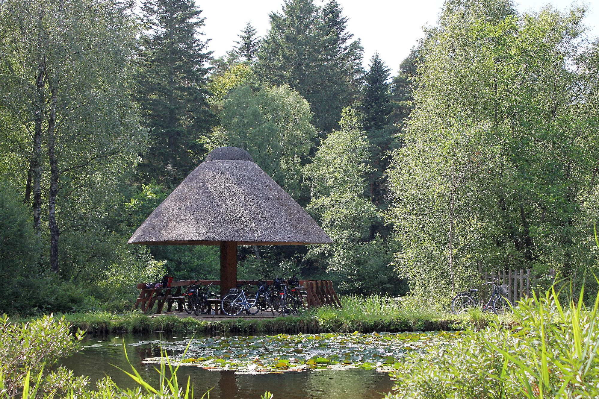 Fahrräder sind an einen reetgedeckten Pavillon gelehnt, der an den Fischteichen im Langenberger Forst zu finden ist